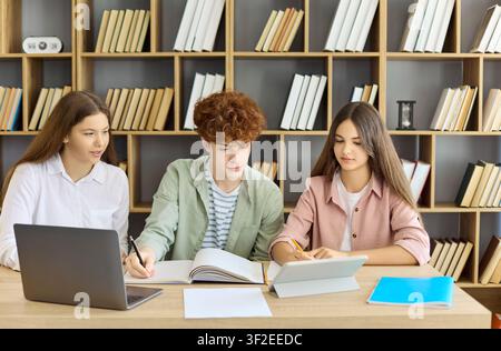 Studierende in der Bibliothek mit Laptop und Tablet, Teamarbeit an einem modernen Projekt Stockfoto