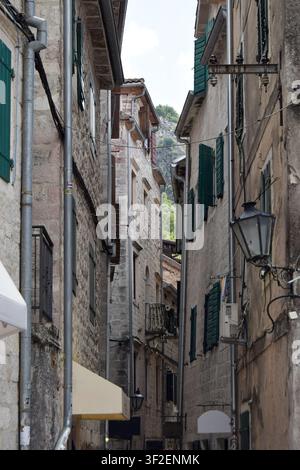 Blick auf eine enge Gasse in der historischen Altstadt von Kotor mit Steinbauten, grünen Fensterläden und hängenden Laternen in Kotor, Gemeinde Kotor, M Stockfoto