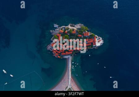 Atemberaubende Aussicht aus der Vogelperspektive auf die malerische Insel Sveti Stefan in Montenegro mit ihren berühmten Gebäuden mit roten Dächern, umgeben von türkisfarbenem Wasser. Szene Stockfoto