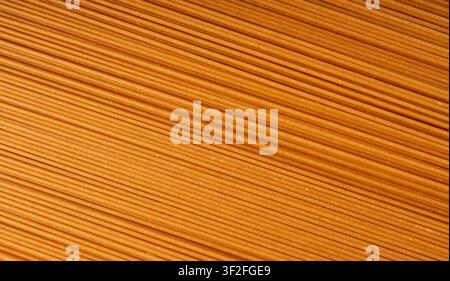 Rohe Vollkornbraune Spaghetti Makrotextur, trockenes Spaghettimuster, lange Weizenudeln Banner, ungekochte italienische Makkaroni-Nudeln Nahaufnahme Stockfoto