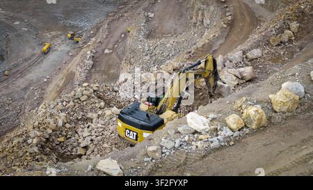 Luftaufnahme einer Steinmine mit gelbem Bagger, der auf felsigem Gelände in Zalas, Woiwodschaft Kleinpolen, Polen arbeitet. Stockfoto
