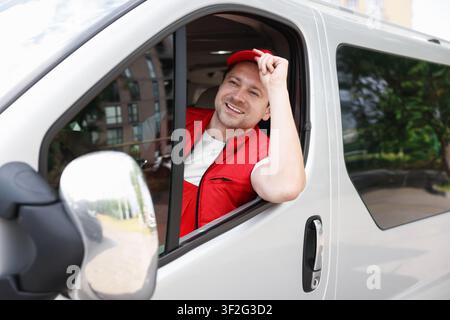 Kurier in Uniform fährt Auto. Lieferdienst Stockfoto