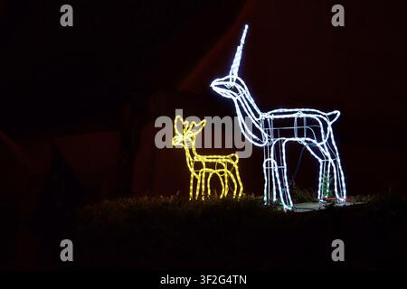 Eine atemberaubende Darstellung von beleuchteten Hirschskulpturen in einem Gartengebiet oder Park im Freien, die eine festliche und verspielte Atmosphäre mit Weiß und Gelb schaffen Stockfoto