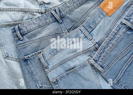 Hellblaue Denimjeans-Stoffturbakgrund mit braunem Ledereinschlag, Mode- und Textilindustrie Stockfoto