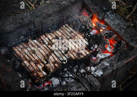 Heißer leerer tragbarer Barbecue Grill mit flammendem Feuer und Kohle auf schwarzem Hintergrund. Warten auf die Platzierung Ihrer Lebensmittel. Nahaufnahme Stockfoto