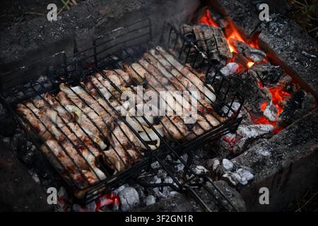 Heißer leerer tragbarer Barbecue Grill mit flammendem Feuer und Kohle auf schwarzem Hintergrund. Warten auf die Platzierung Ihrer Lebensmittel. Nahaufnahme Stockfoto