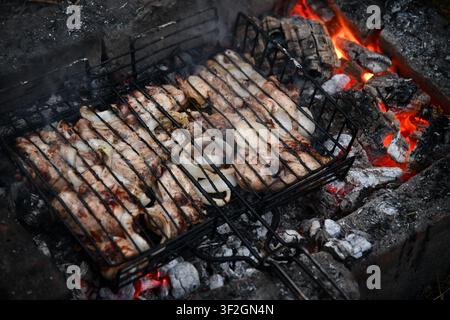 Heißer leerer tragbarer Barbecue Grill mit flammendem Feuer und Kohle auf schwarzem Hintergrund. Warten auf die Platzierung Ihrer Lebensmittel. Nahaufnahme Stockfoto