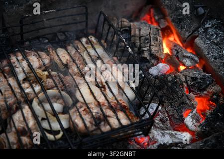 Heißer leerer tragbarer Barbecue Grill mit flammendem Feuer und Kohle auf schwarzem Hintergrund. Warten auf die Platzierung Ihrer Lebensmittel. Nahaufnahme Stockfoto
