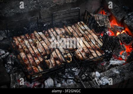 Heißer leerer tragbarer Barbecue Grill mit flammendem Feuer und Kohle auf schwarzem Hintergrund. Warten auf die Platzierung Ihrer Lebensmittel. Nahaufnahme Stockfoto