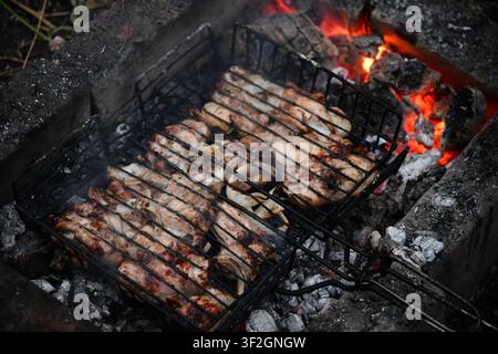 Heißer leerer tragbarer Barbecue Grill mit flammendem Feuer und Kohle auf schwarzem Hintergrund. Warten auf die Platzierung Ihrer Lebensmittel. Nahaufnahme Stockfoto
