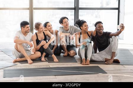 Glückliche Yogakursmitglieder, die nach dem Training Selfie auf dem Smartphone machen Im Studio Stockfoto