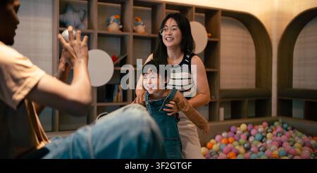 Glückliche Familie Eltern Kind spielen zusammen und haben Spaß in einem modernen Indoor-Spielbereich Stockfoto