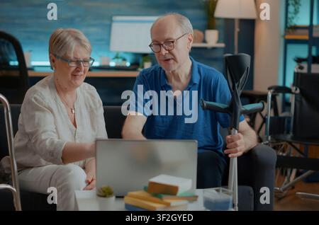 Seniorenpaar feiert Erfolg bei der Laptop-Zusammenarbeit in einem klinischen Büro, verbindet Patientenbesprechung, Diagnosereview und professionelle Gesundheitsversorgung. Stockfoto
