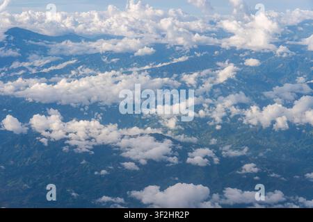 Flauschige weiße Wolken schweben über üppigen grünen Bergen und tiefen Tälern und schaffen eine atemberaubende Luftperspektive, die Themen der Natur repräsentiert, en Stockfoto
