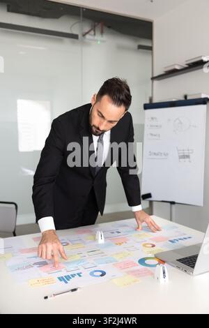 Geschäftsmann analysiert Marketingdaten, plant Strategie, überprüft gedruckte Materialien Stockfoto