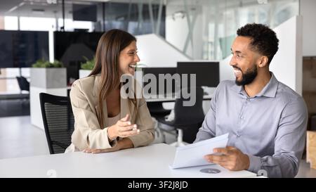 Lächelnde Kollegen führen ein lockeres Gespräch im Büro Stockfoto