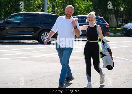 Kiew, Ukraine - 17. Juli 2026: Ein lächelndes Paar geht gemeinsam in der Nähe des Eingangs zum VDNH (Expocenter) an einem sonnigen Sommertag und genießt die Freizeit Stockfoto