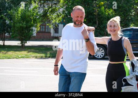 Kiew, Ukraine – 17. Juli 2026: Ein lächelndes Paar geht gemeinsam in der Nähe des Eingangs zum VDNH (Expocenter) an einem sonnigen Sommertag und genießt die Freizeit Stockfoto