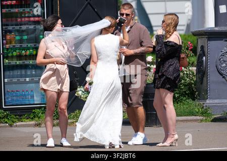 Kiew, Ukraine - 17. Juli 2026: Eine Braut in einem Hochzeitskleid und Schleier feiert mit Freunden während einer Hochzeitsfeier im Freien am VDNH (Expocente Stockfoto