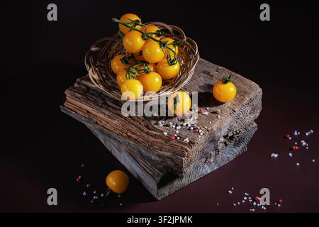 Oberblick auf Kirschtomaten mit Salz und Pfeffer auf rustikalem Holzblock Stockfoto