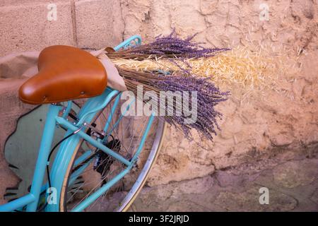 Vintage-blaues Fahrrad mit einem Strauß getrocknetem Lavendel und Weizen auf einem Straßenmarktstand während des Lavendel-Festivals in Brihuega Stockfoto