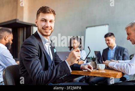 Junger Unternehmer Sitzt Am Tisch Mit Geschäftspartnern Im Büro Stockfoto
