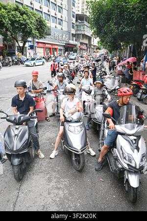 (260719) -- CHONGQING, 19. Juli 2026 (Xinhua) -- Motorradfreiwillige warten in einer Schlange an einem Sammelpunkt, um Nachschub und Personal in den autonomen Bezirk Pengshui Miao und Tujia von Chongqing, Südwestchina, am 19. Juli 2026 zu liefern. Um 9:08 Uhr am Freitag kam es im Unterbezirk Hanjia von Pengshui zu einem durch Regenfall ausgelösten Bergrutsch, der mehr als 10 Wohnhäuser verschüttete, während einige Anwohner eingeschlossen und vermisst wurden. China aktivierte eine nationale Notfallreaktion der Stufe II für geologische Katastrophen. Mehrere Rettungstruppen, einschließlich Notfallreaktion, Brandbekämpfung und Stockfoto