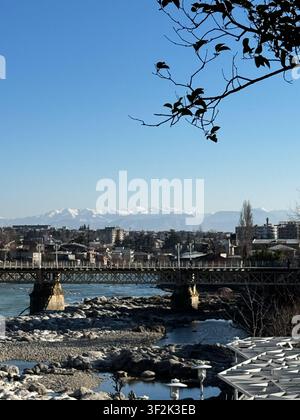 Brücke über den Rioni-Fluss mit Blick auf die schneebedeckten Kaukasus-Berge in Kutaisi, Georgien Stockfoto