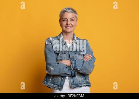 Porträt einer selbstbewussten Frau mittleren Alters, die mit gefalteten Armen posiert Stockfoto