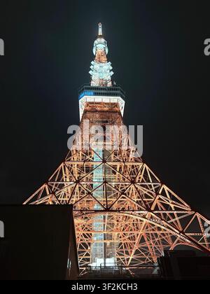 12. August 2025, Minato, Tokio, Japan – Die orangefarbene Stahlgitterkonstruktion des Tokyo Tower wurde nachts aus direkter Unterseite fotografiert, dramatische diagonale Perspektive. Stockfoto