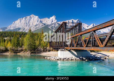 Historische Canmore-Enginebrücke über den türkisfarbenen Bow River mit Mount Rundle und den Rocky Mountains im Hintergrund, Alberta, Kanada. Stockfoto