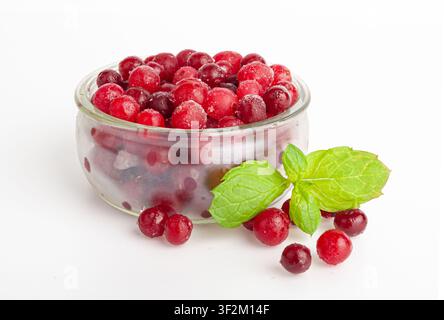 Gefrorene Preiselbeere isoliert, verstreute eisige Cowberry, Schnee-Himbeere in Glasschale, rote Viburnum-Beeren, gefrorene Preiselbeere auf weißem Hintergrund Stockfoto