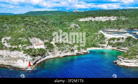 Pittoreske Landschaft mit der türkisfarbenen Bucht von Bonifacio und dem roten Leuchtturm in Korsika, Frankreich Stockfoto