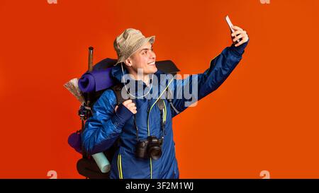 Reisender in Jacke mit großem Rucksack, der selfie mitnimmt Stockfoto