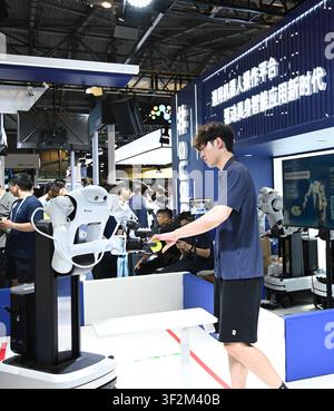 Shanghai, China. 19. Juli 2026. Ein Roboter nimmt während der Welt-AI-Konferenz 2026 in Shanghai, Ostchina, am 19. Juli 2026 ein Objekt von einem Mitarbeiter entgegen. Die laufende Welt-AI-Konferenz 2026 entpuppt sich als ein hart umkämpfter Markt für allgemeine verkörperte KI-Produkte von mehr als 200 Anbietern. Es bezieht sich auf ein allgemeines Intelligenzsystem, das es Robotern ermöglicht, variable Aufgaben auszuführen und sich an verschiedene Anwendungsszenarien anzupassen. Credit: Huang Xiaoyong/Xinhua/Alamy Live News Stockfoto