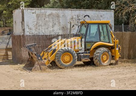 Gelber Bagger, der auf einer Baustelle im Tageslicht geparkt ist. Penaguila, Alicante, Spanien - 12. Juli 2026. Stockfoto