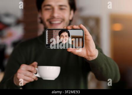 Junger schöner Mann, der Selfie beim Kaffeetrinken nimmt Stockfoto