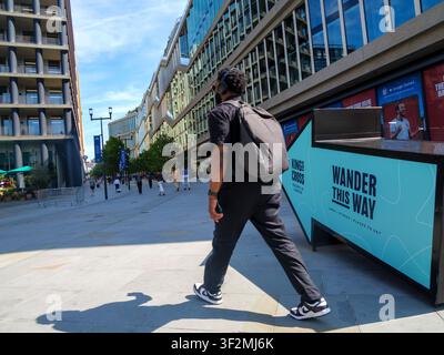 Ein Fußgänger geht an einem auffälligen Richtungsschild mit der Aufschrift "Wander this Way" vorbei, das Besucher zu den Einzelhandelsgeschäften, lebendigen Bars und Restaurants der King's Cross-Entwicklung in London, UK, führt Stockfoto