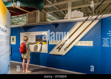 Ein Besucher mit einem roten Rucksack betrachtet ein Kanu und traditionelle Angelausrüstung in der Ausstellung ‚Ta'n me'j Tel-keknuo'ltiek – Wie einzigartig wir immer noch sind‘, die die Verbindung der Mi'kmaq zum Land und zum Meer erforscht, im Maritime Museum of the Atlantic in Halifax, Nova Scotia, Kanada. Halifax, Nova Scotia, Kanada Stockfoto
