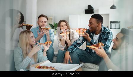 Gruppe von Freunden, die gemeinsam zu Hause Pizza mit lächelnden Gesichtern genießen, feiern Stockfoto