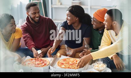 Gruppe von jungen, vielfältigen Freunden, die gemeinsam zu Hause Pizza genießen, glückliche lächelnde Gesichter Stockfoto