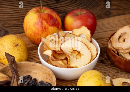Trockene Apfelscheiben auf Holztisch. Getrocknete Apfelchips, gesunder Obstsnack in Schüssel, dehydrierte Gourmet-Ringe, knusprige entkernte Süßbirnenchips auf rustikalem Bac Stockfoto