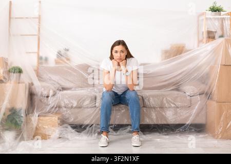 Junge traurige Frau, unglücklich über die neue Reparatur in ihrem Zuhause Stockfoto