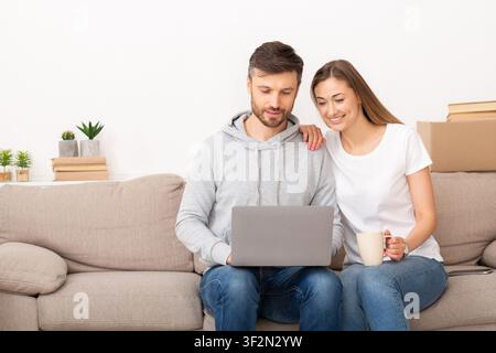 Junge Paare, die mit einem Laptop ein intelligentes Zuhause einrichten Stockfoto