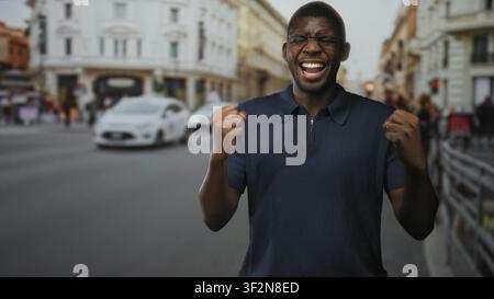 Mann mit geballten Fäusten, schreiend und lachend auf einer belebten europäischen Straße, mit Brille und Marinepolo, mit aufgerissenem Mund in einer kurzen Sequenz; Stockfoto