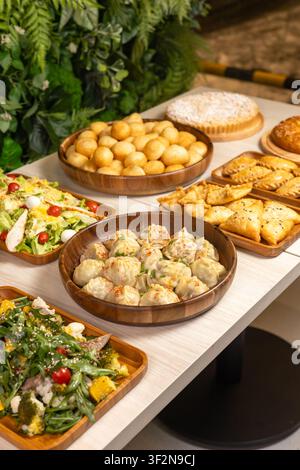 Eine vertikale Hochwinkel-Studioaufnahme eines traditionellen zentralasiatischen Festtisches mit Manti-Dumplings, goldenen Baursak-Teigbällchen und Samsa-Gebäck Stockfoto