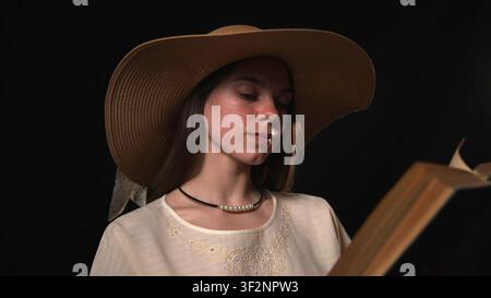 Junge Frau liest ein Buch in einem dramatischen Studio-Porträt Stockfoto