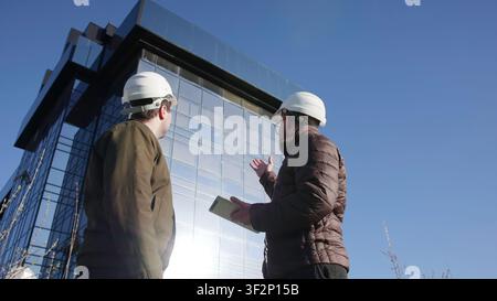 Bauingenieure und Architekt diskutieren Fragen der strukturellen Integrität und Sicherheitsaspekte auf der Baustelle. Medien Stockfoto