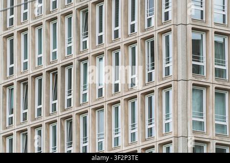 Minimalistische Bürofassade mit sich wiederholendem Fensterpattern und klaren architektonischen Linien, geometrische Formen, abstrakte architektonische Komposition eines Modernen Stockfoto