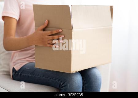 Afro-amerikanisches Mädchen, das einen Pappkarton auf den Knien hält Stockfoto